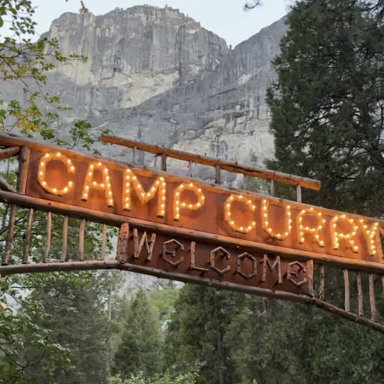 Curry Village's welcome sign "Camp Curry" with granite cliffs behind it.