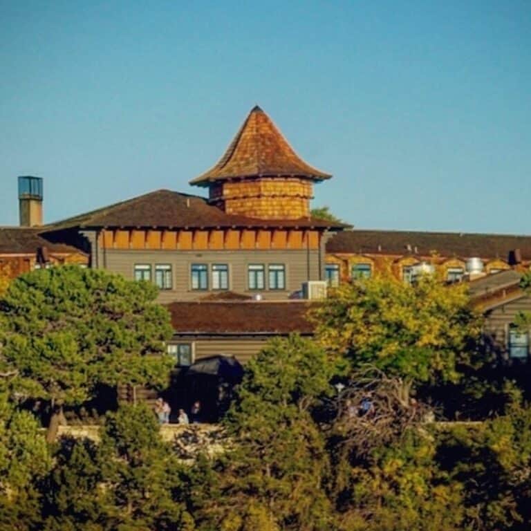 Exterior view of the El Tovar Hotel on a sunny day with blue skies overhead.