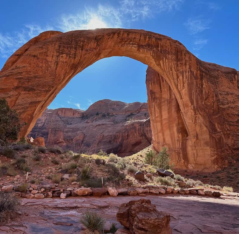 Rainbow Bridge on a sunny day with the sun hidden behind the massive stone arch.
