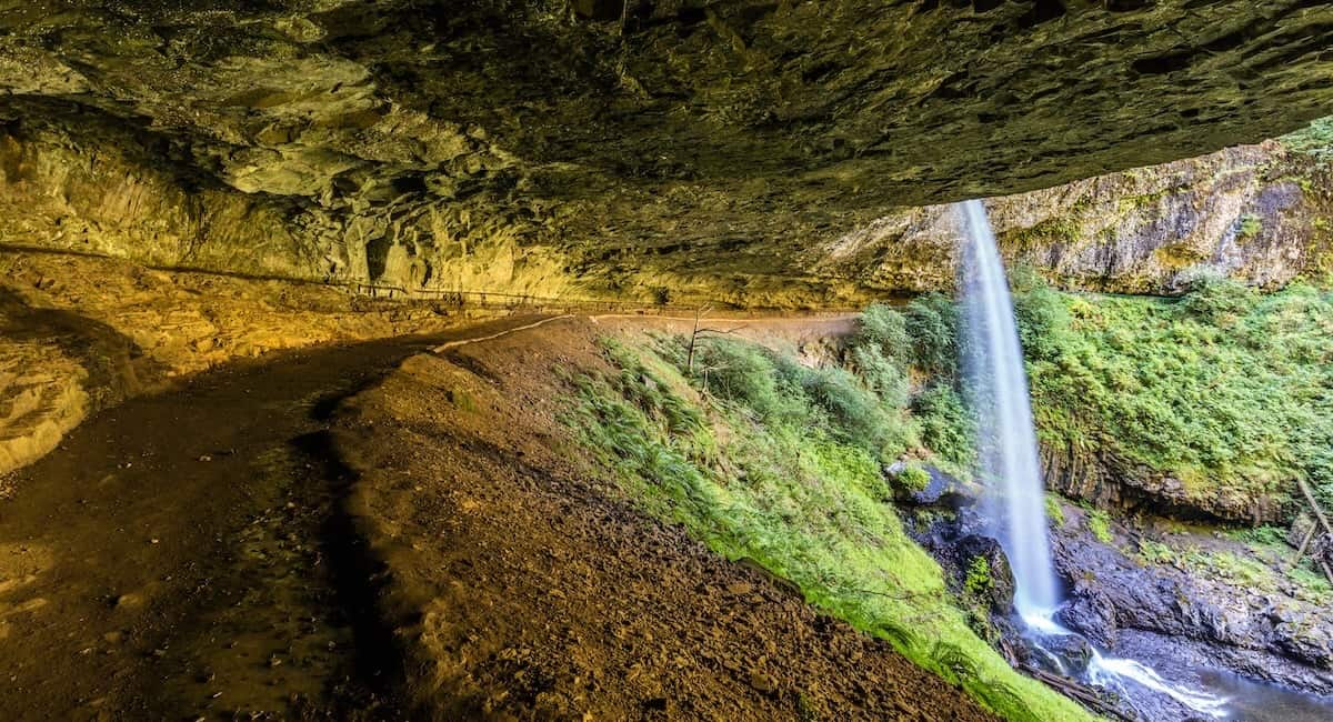 walking behind a waterfall as it cascades over a cliff